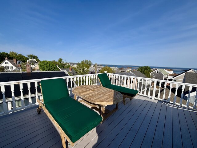 Roof deck with white raining two lunge chairs, table, town and bay views