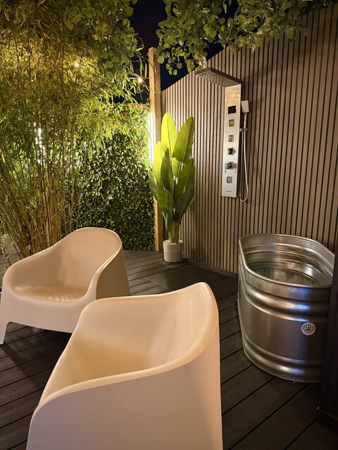 Close-up view of the outdoor shower, plunge pool and surrounding jungle-style plants in the sheltered relaxation area at The Secret Garden Glamping.