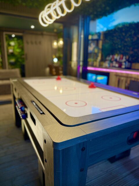 Luxury glamping games area featuring an air hockey table with swirl lights overhead and a private outdoor bar at The Secret Garden Glamping.