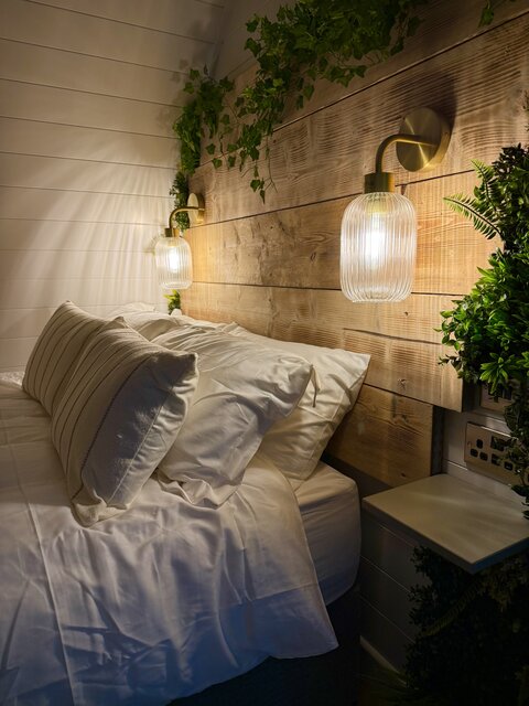 “The Horizon bedroom at The Secret Garden Glamping showing the top and middle of the bed with perfectly arranged pillows and crisp white sheets exuding luxury. 