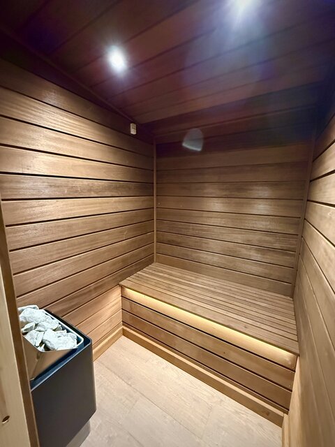 “The Horizon wellness area at The Secret Garden Glamping showcasing a premium sauna and steam room, with a drawer elegantly stocked with soft, plush robes and towels.