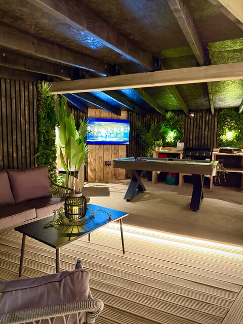 “The Horizon indoor lounge at The Secret Garden Glamping, featuring an opulent seating area adorned with plush pillows, a central rug, and a table with a decorative plant. 