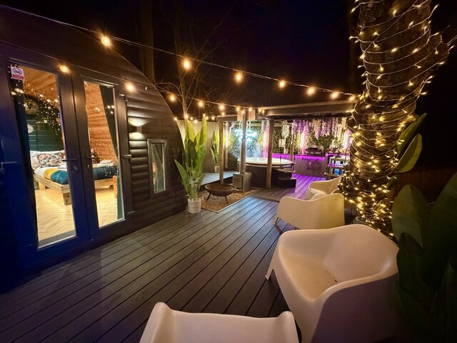 “The Keep outdoor area at The Secret Garden Glamping, illuminated by hanging lights that highlight the full space, creating a warm, atmospheric setting for relaxing evenings outdoors.”