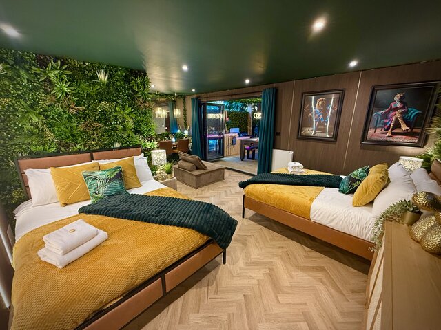 Luxury glamping outdoor area with covered hot tub, wall-mounted smart TV, comfortable seating and stylish artificial jungle-themed decor at The Secret Garden Glamping.
