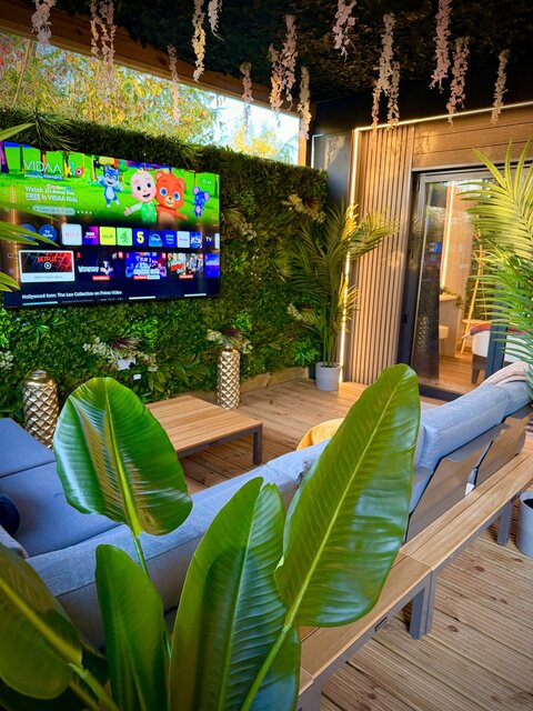 “The Blossom pod outdoor seating area at The Secret Garden Glamping, featuring two perfectly positioned couches around a luxurious coffee table that complements the golden-brown decking.