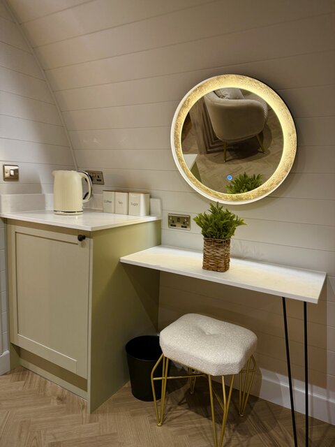 “The Horizon room at The Secret Garden Glamping featuring a dresser with a large mirror, a kettle on the left for making coffee, and a designated area to prepare for the day.