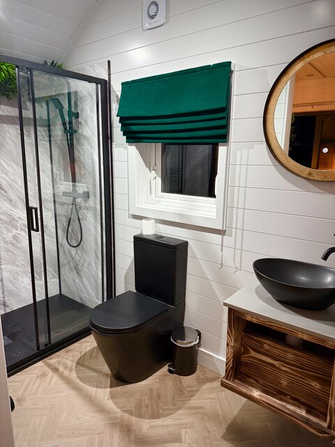 “Horizon pod bathroom at The Secret Garden Glamping featuring a sleek black toilet, a stylish black bowl sink, and a spacious walk-in shower, all designed to enhance the luxurious nature.