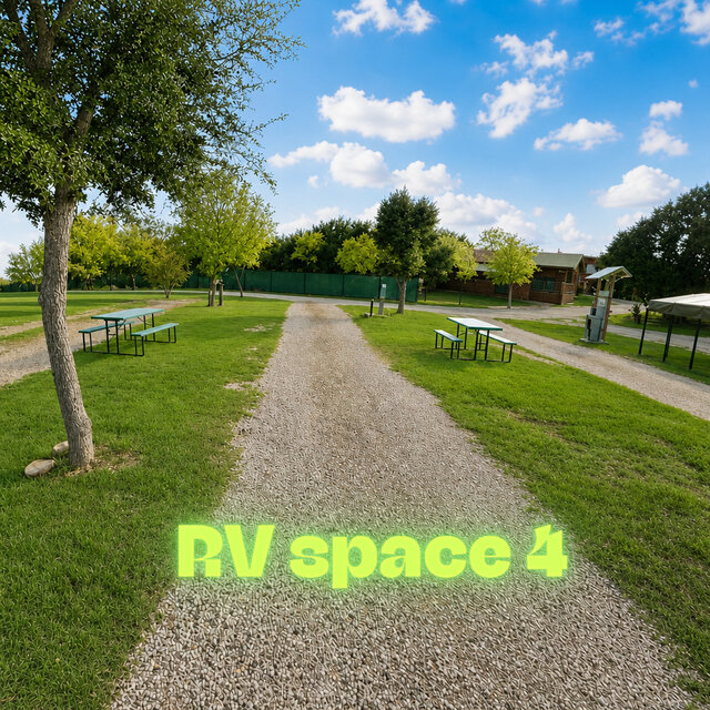 Shadow Cruiser RV on Space 4 with awning extended, surrounded by green grass and Hill Country trees at Al’s Hideaway.
