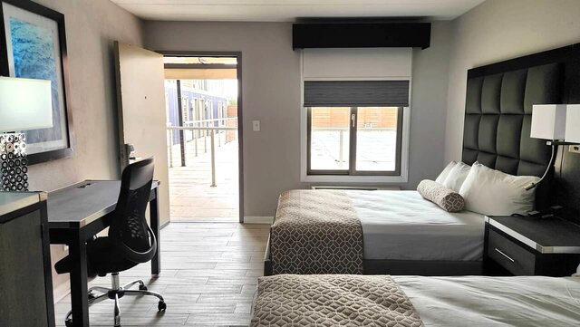 room with two double beds with exterior door open showing pool desk outside