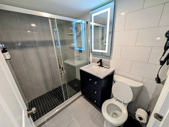 Bathroom showing vanity, toilet and walking shower