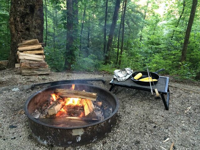 a campsite with a fire pit and wood pile