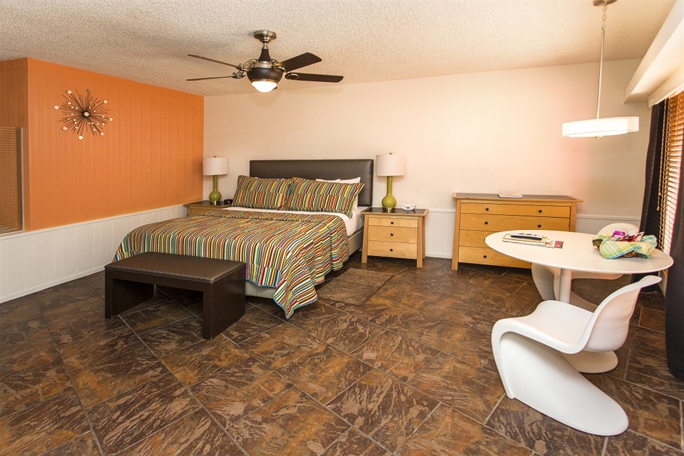A wide view of a hotel room with a bed, desk, and chair