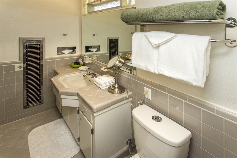 A bathroom with a toilet, sink, and tiled walls and floor.