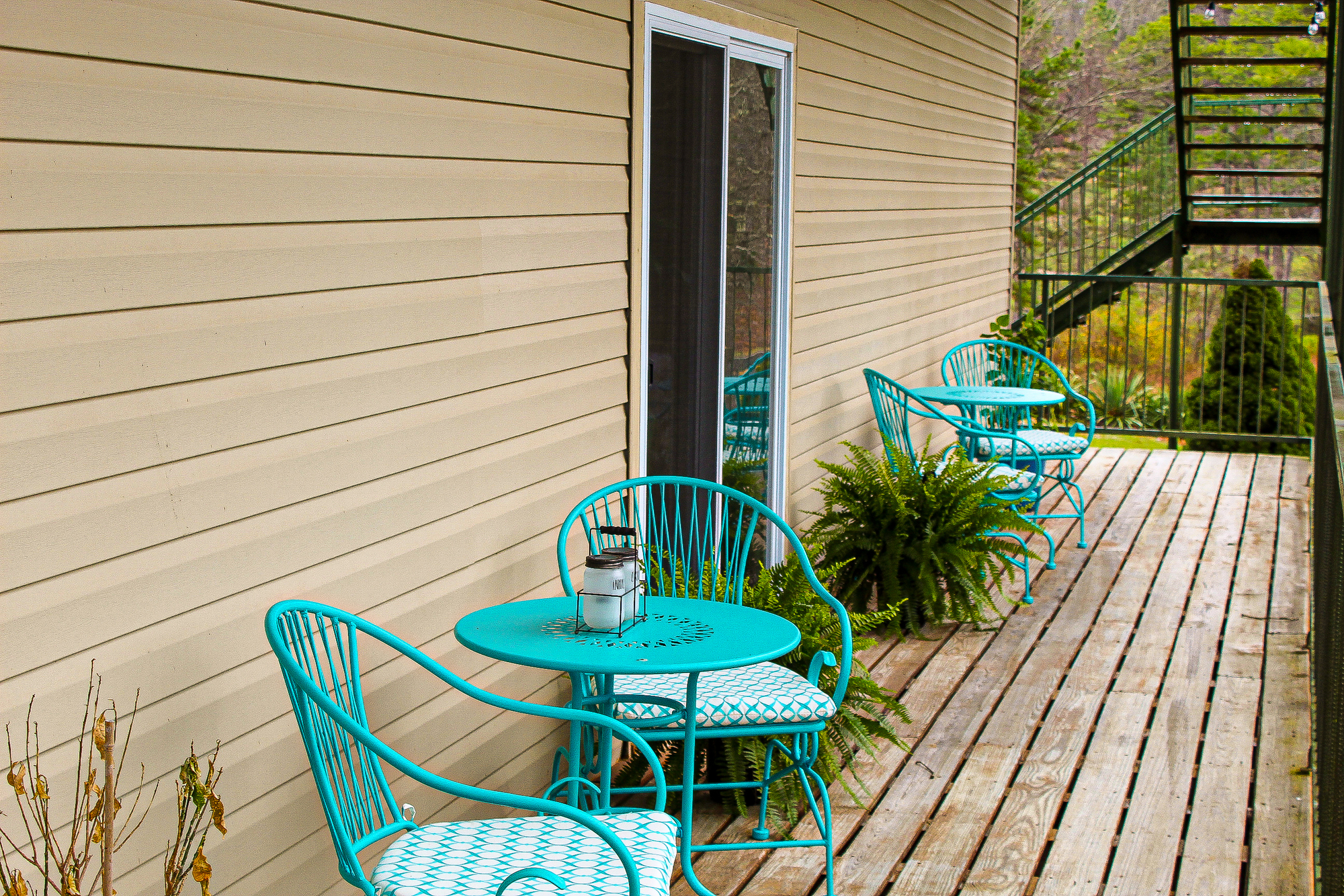 A wooden deck with teal patio furniture and plants